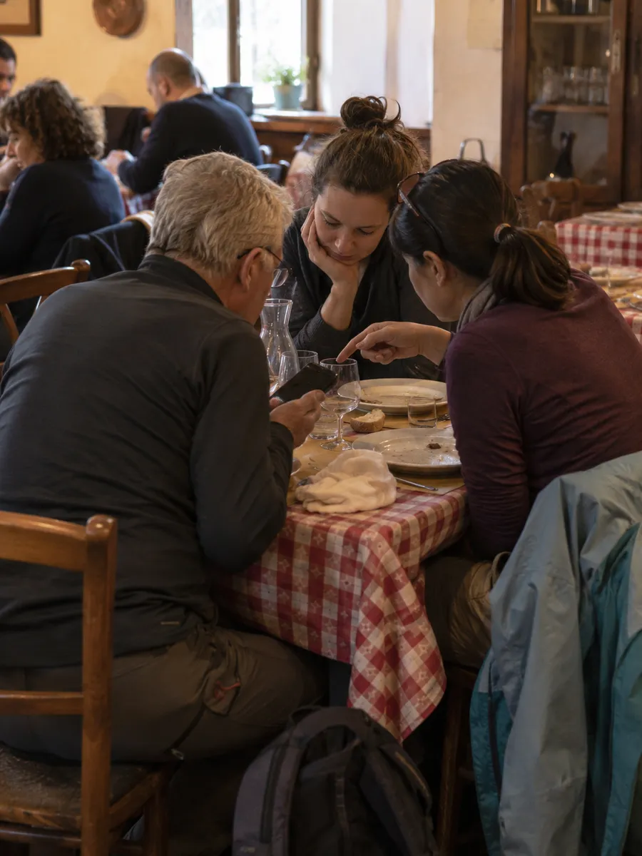 Gruppo di turisti stranieri al tavolo che guarda insieme il menu sul telefono